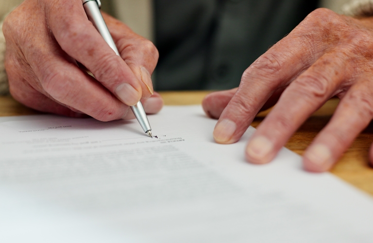senior man signs a document