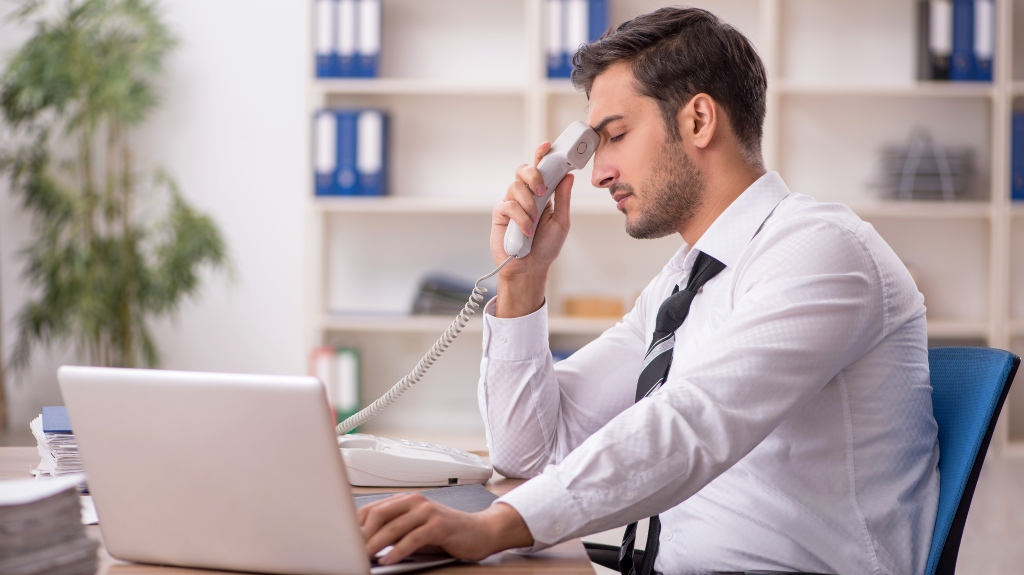 upset man sits at computer after call