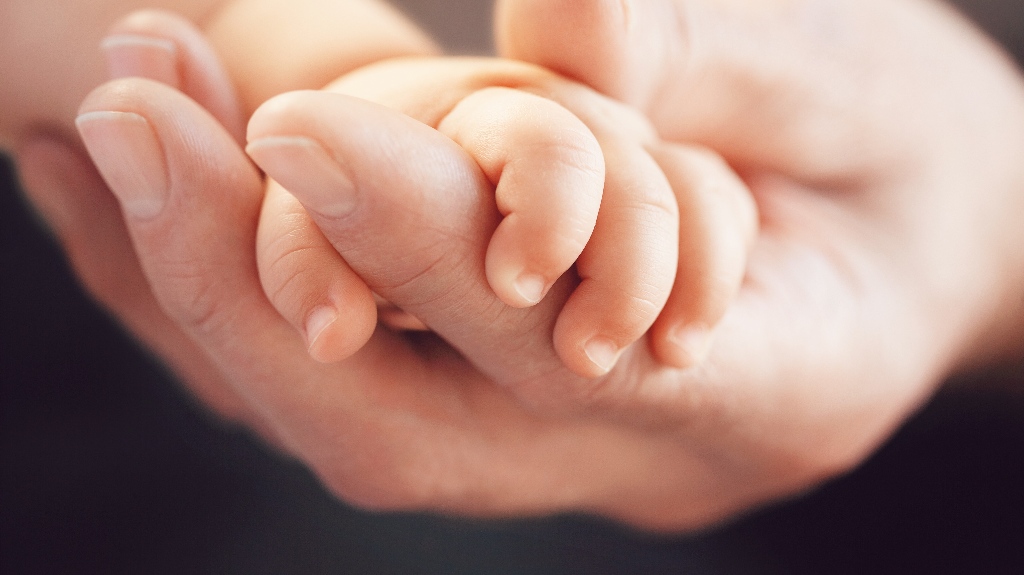 Closeup of a baby holding man's finger