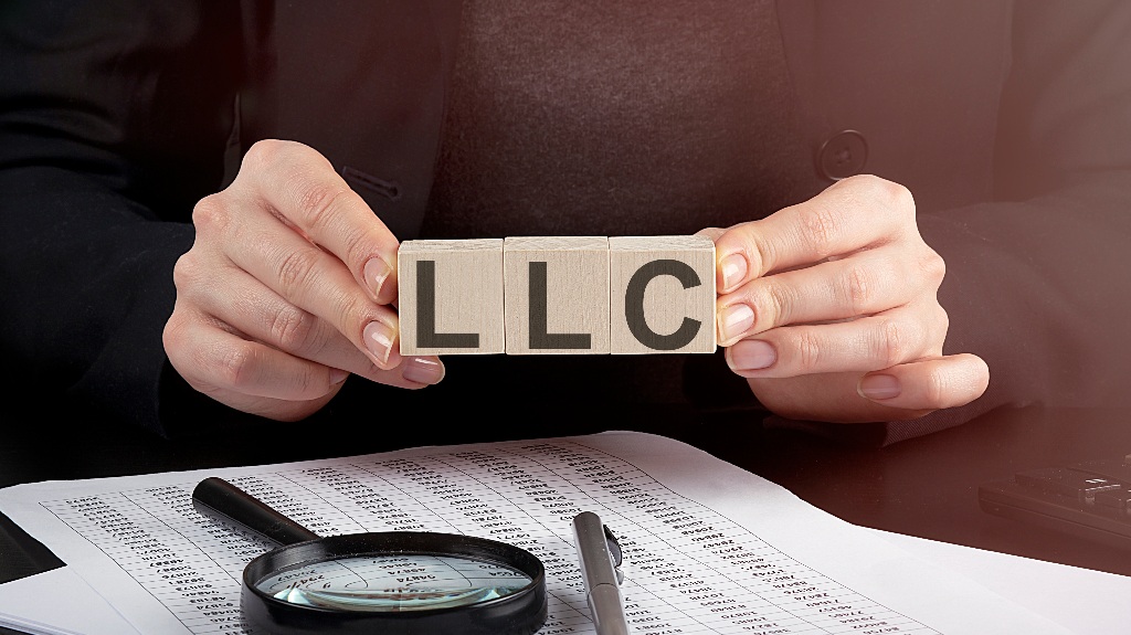 woman holding wooden block with text LLC