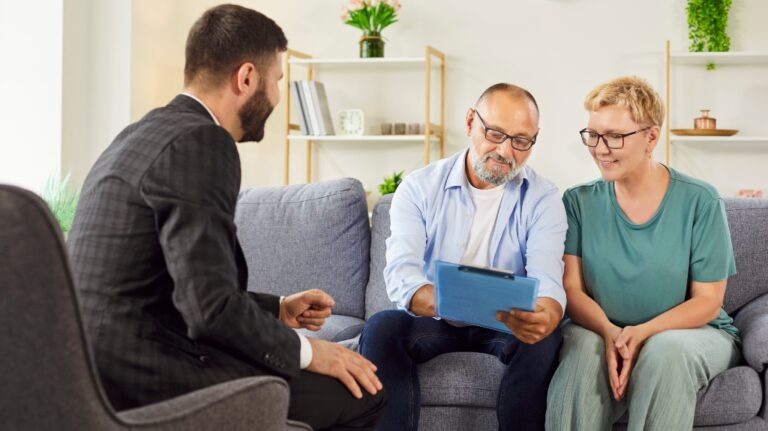 Smiling elderly couple meets agent at home, reviewing documents